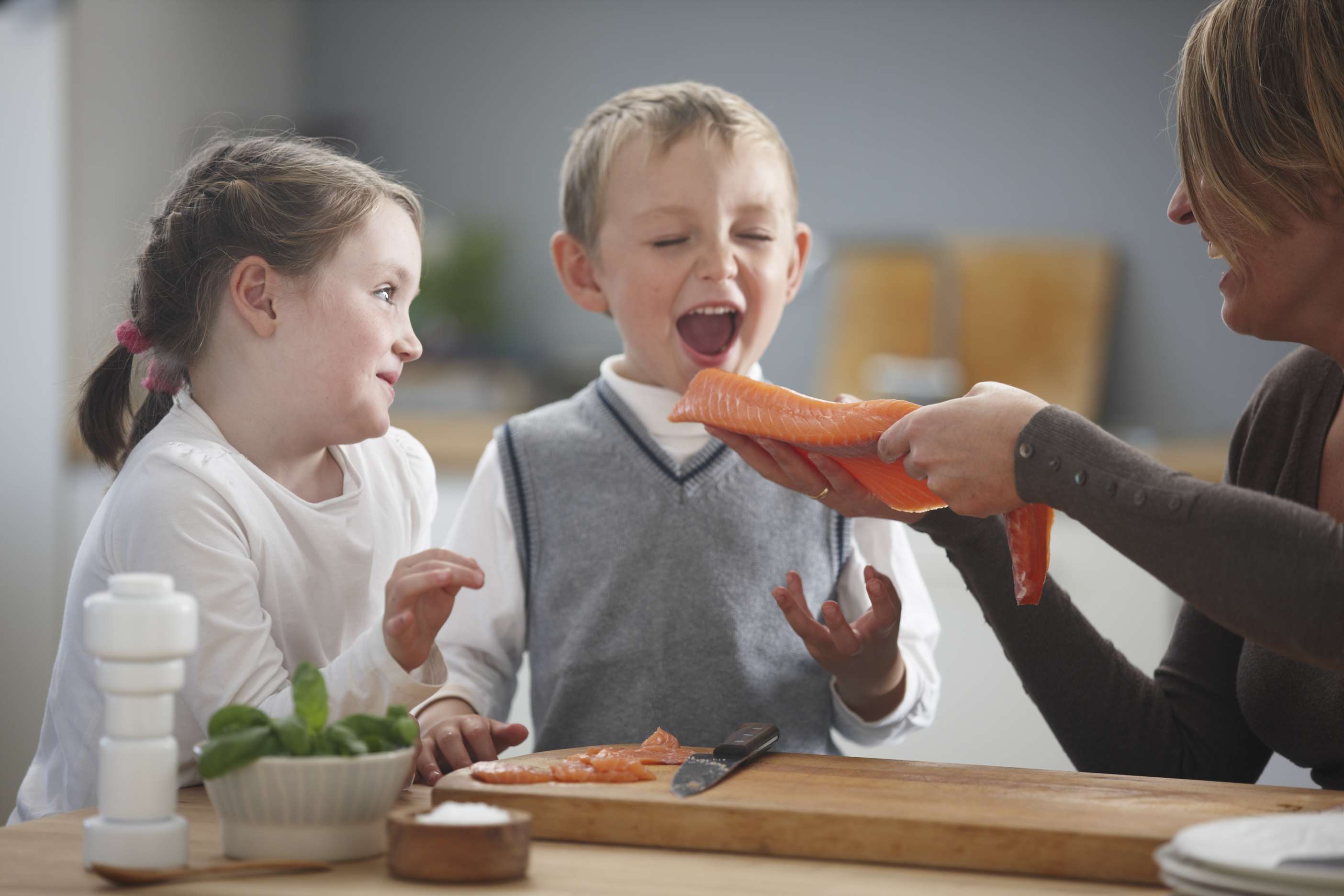 Barn og kvinne på kjøkkenet med laks